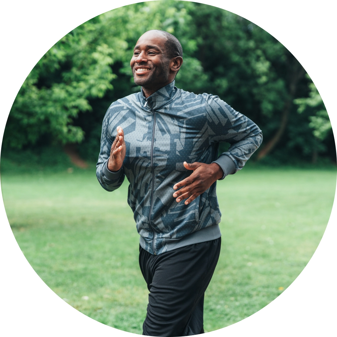 African American man jogging outdoors in park wearing athletic gear and headphones