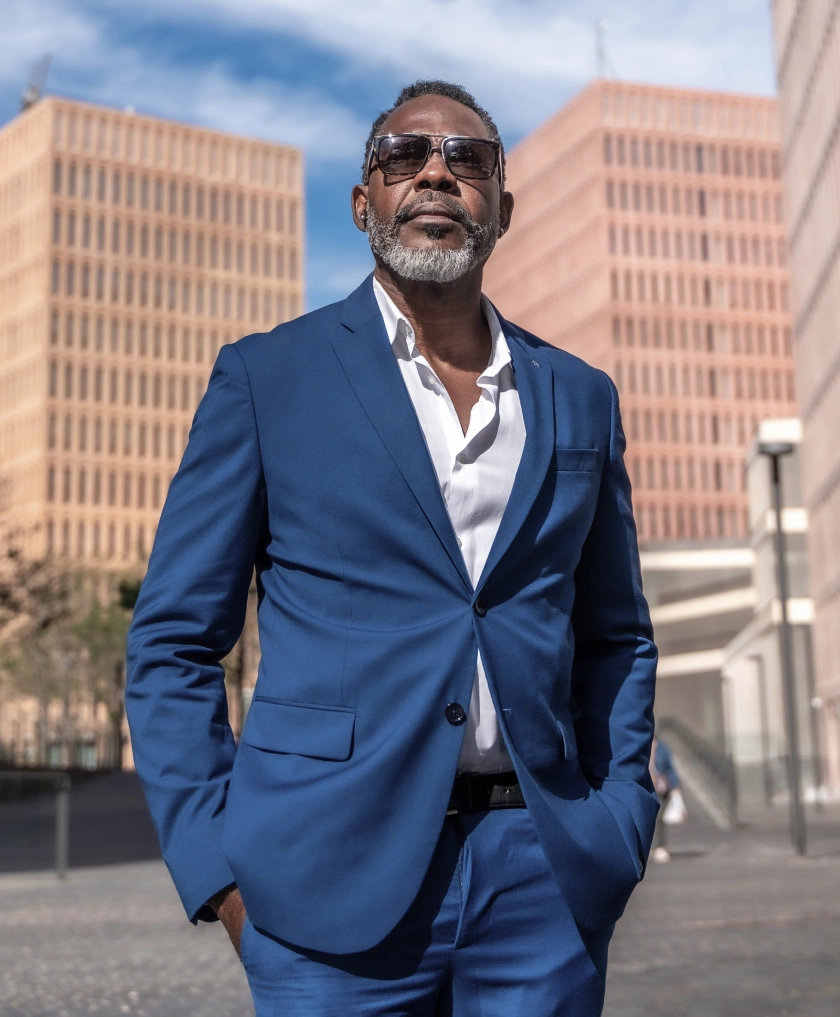 Professional Black businessman in blue suit and sunglasses standing confidently in urban downtown setting - in Clifton, NJ