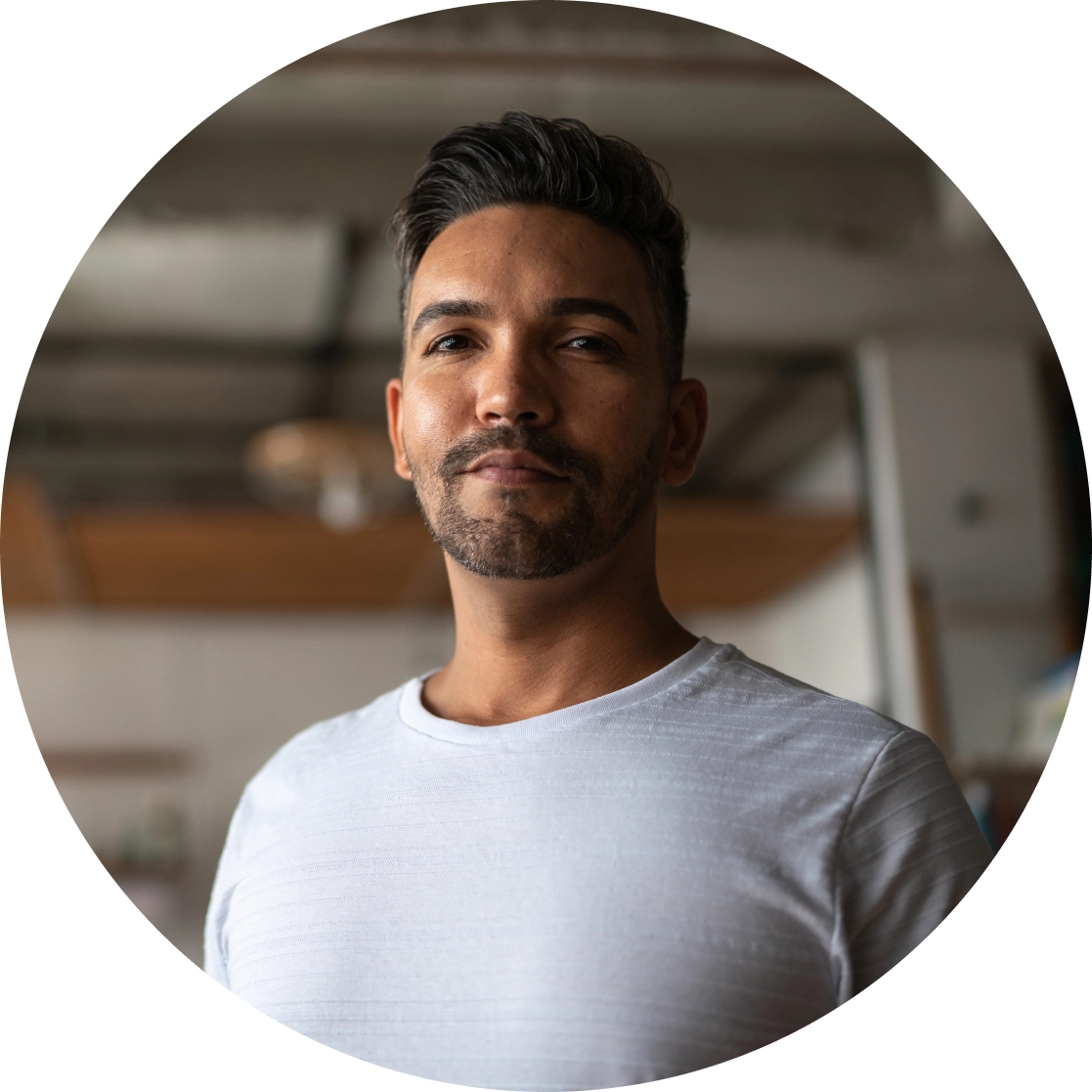 Professional headshot of confident man in white t-shirt with modern interior background