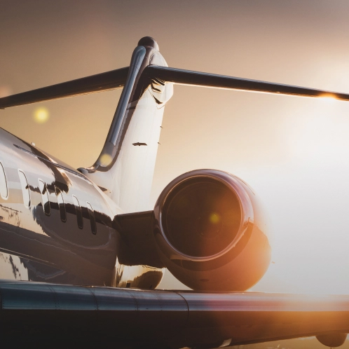 Private jet on tarmac at sunset with glowing engine and T-tail visible against golden sky - Travel in Clifton, NJ