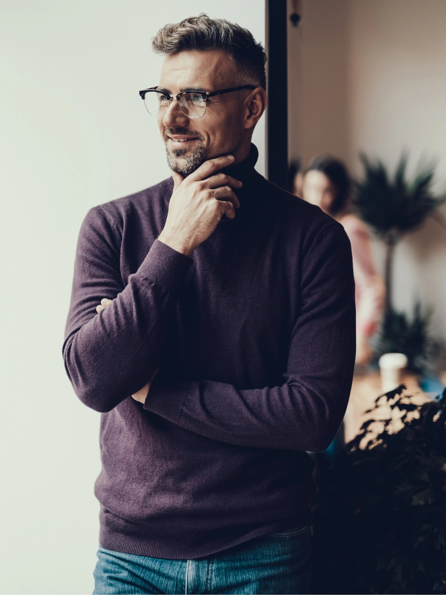 Professional man in glasses and purple sweater in thoughtful pose at modern office space - in Clifton, NJ