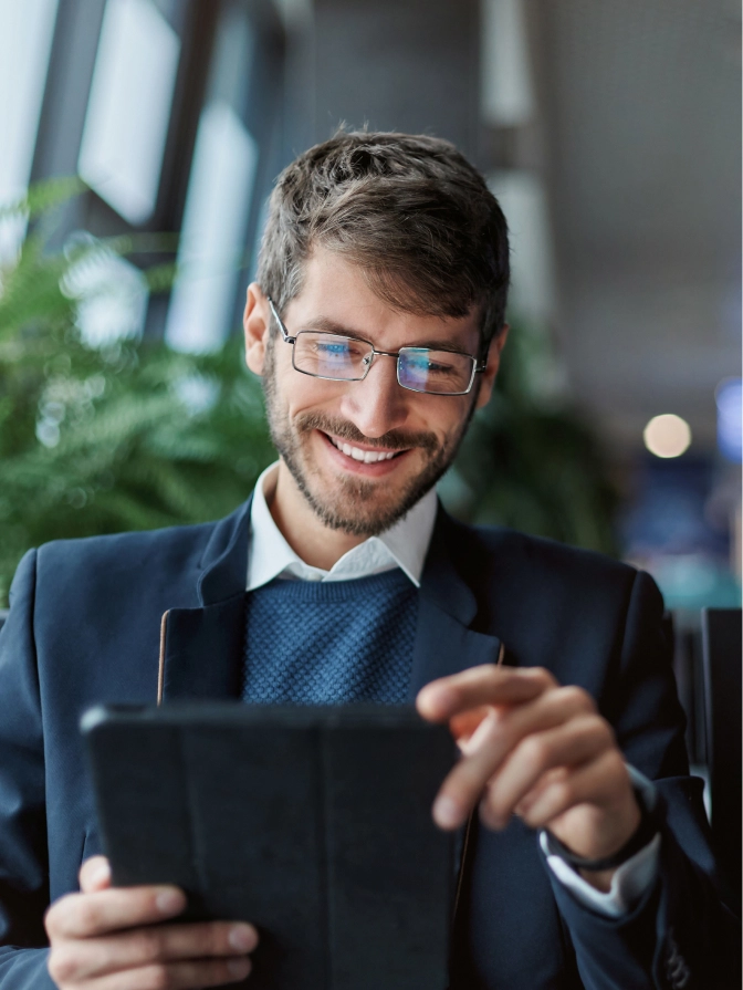 Professional businessman in suit and glasses smiling while using digital tablet in modern office setting - in Clifton, NJ