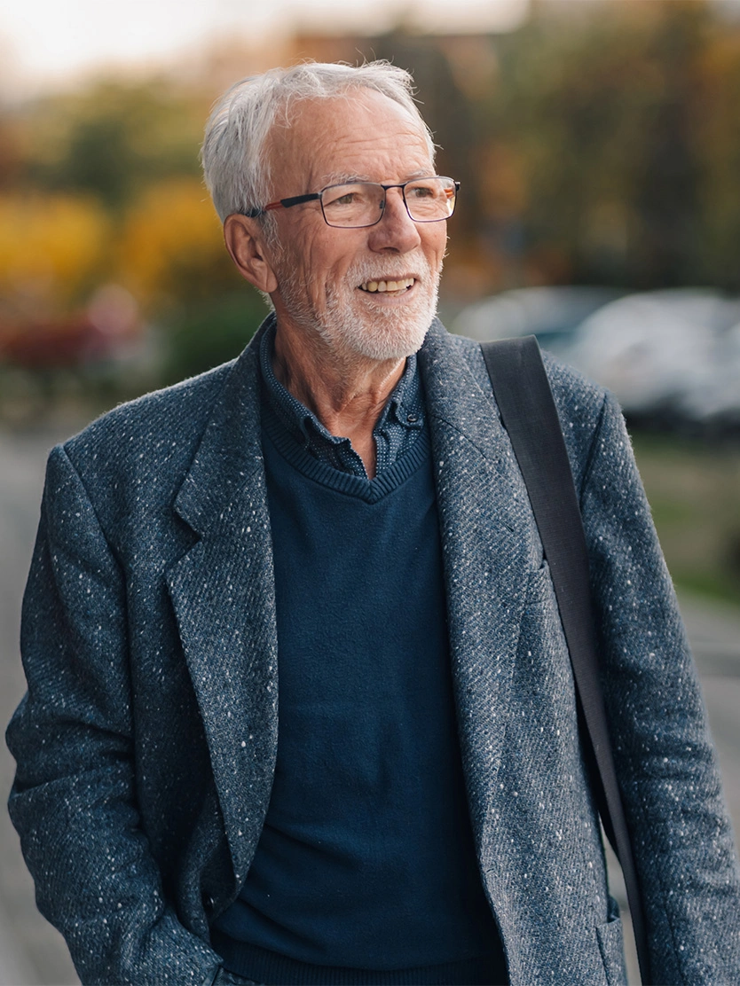 Smiling senior businessman wearing glasses and blue blazer outdoors in natural setting - Artificial urinary spincter in Clifton, NJ